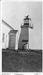 Lighthouse tower and part of dwelling, Cape Breton. Unidentified woman and young boy standing near side door of house 1911