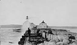 Lighthouse and lightkeeper's dwelling. Protective cribbing in the foreground being maintained 1926