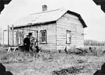Mr. and Mrs. S. Delblanc and one of their children in front of their farmhouse at S.W. 12-37-26-West 1st meridian. Swedish settlers, they have about 135 acres, of which about 10 are under cultivation. Minitonas district, Manitoba 1927
