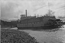 Old paddle steamer 'Distributor' of the Hudson Bay Co. on the Mackenzie River, waiting for logs as fuel once a day on his route to the North [graphic material] 1933.