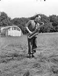 Saxophonist Private Gordon Murray of the Canadian Army Show practicing in a field outside the Show's production centre, Guildford, England, 21 June 1945 June 21, 1945.