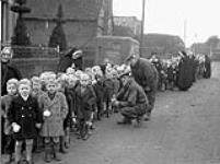 Private M.M. Barnhart and Lance-Corporal C.G. Balazs talking with children attending a Christmas party sponsored by the Argyll and Sutherland Highlanders of Canada, Elshout, Netherlands, 17 December 1944 Deember 17, 1944