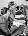 Captain S.C. Ritchie of Canadian Military Headquarters (CMHQ) and engineer Betty Gates in the control room during a Canadian Army Show recording session, London, England, 29 June 1945 June 29, 1945.
