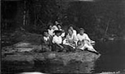 Unidentified group of young women sitting on edge of riverbank, Muskoka Lakesg ca. 1904