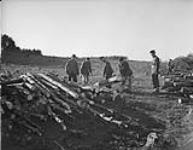Concentration camp - Captain C. J. Burmham with working party in the woods piling logs 30 Ot. 1945