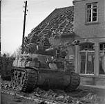Sherman tank with its 76mm gun awaits order to proceed with the infantry - 4th Canadian Armed Division chasing German paratroopers out of town 11 Apr. 1945