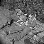 Privates R.E. Lodwick and Mac McKinnon of the Lincoln and Welland Regiment resting after driving German paratroops out of Wertle, Germany, 11 April 1945 April 11, 1945.