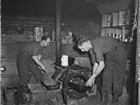 Officers of the 5th Field Regiment in the underground cook house - Captain Randall Morse, frying onions, and Captain Hartley Craig pulling out the roast from the oven 1 - 2 Feb. 1945