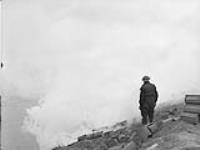 CANADIANS IN HOLLAND. Offensive towards Cleve. Man on hill watches laying of smoke screen on dyke near the Rhine River 10 Feb. 1945