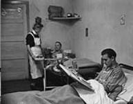 Men's ward of an underground Dutch hospital. (L-R): Nurse Henry Blom, patients Joseph Saedt, Joseph Loeffen 2 Jan 1945