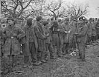 Private A.N. Geroux, Argyle and Sutherland Regiment keeps guard on a group of Jerry prisoners 26 Feb. 1945