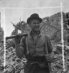 Private H. Koebe of the 9th Canadian Infantry Brigade helping to clear rubble, Carpiquet, France, 12 July 1944 July 12, 1944.