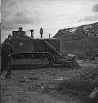 Bulldozer in action widening the cross-roads immediately after it was cleared by the sappers of the Royal Canadian Engineers 09-Jul-44