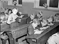 "Education in occupied Germany: Class in progress with little boy reading from a bible" 30 Aug. 1945
