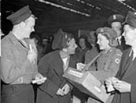 Arrival of the survivors of the sinking of H.M.C.S. ATHABASKAN off the coast of France in April 1944. They were then taken prisoner in Germany. The Canadian Red Cross girls were on hand to greet themwith candy and cigarettes May 1945