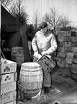 Private Hugh Dryden of No.35 Canadian Army Troops Composite Company, Royal Canadian Army Service Corps (R.C.A.S.C.), preparing a drum of powdered milk, Nijmegen, Netherlands, 14 February 1945 February 14, 1945.