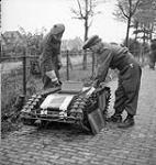 Privates M. Voske and H. Browne of The Calgary Highlanders examining a captured German radio-controlled Beetle tank [Goliath remote controlled demolition vehicle], Goes, Netherlands, 30 October 1944 October 30, 1944.