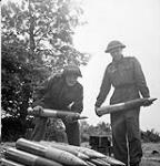 Gunners J.R. Robinson and L.T. Groves, both of 34 Battery, 14th Field Regiment, Royal Canadian Artillery (R.C.A.), stacking 105mm. shells in Normandy, France, 20 June 1944 June 20, 1944.