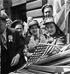 Canadian soldiers and members of the Canadian Women's Army Corps (C.W.A.C.) buying flags to wave in V-E Day celebrations, London, England, 8 May 1945 May 8, 1945