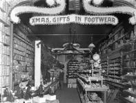 Interior of combined china and footwear store, decorated for Christmas ca. 1902