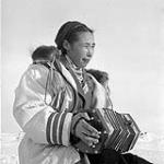 Inuit woman, Martha, playing the concertina, Resolute Bay (Qausuittuq), Nunavut, [The woman in this photograph has been identified as Edith Patsauq] March 1956.
