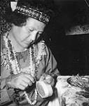 [Ojibway woman attaching quills to the bottom part of a quill box]. Original title: Birch Bank Crafts. Ogibway women attaching quills to bottom part of quill box [between 1900-1976]