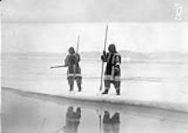 Inuit women fishing at the edge of the ice flow with three-prong fishing spears, N.W.T. [Nunavut], ca. 1932 c.a. 1932.