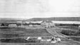 L'école industrielle indienne de Fort Qu'appelle avec des tentes, [des charrettes de la rivière Rouge] et des tipis à l'extérieur de la clôture, Lebret, Saskatchewan, [mai 1885 ?] 1885?.