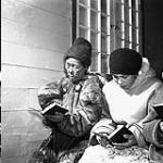 Inuit women attending service at St. Aidan's Anglican mission in Baker Lake. [The older woman on the left is Aulinguaq, and the woman in the white parka is Isumataq.] March 1946.