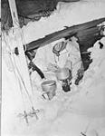 Unidentified Forceman of the First Special Service Force preparing rations in an improvised shelter during cold weather survival training, Blossburg, Montana, United States, January 1943 January 1943.