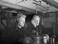 R. Cosburn and Lieutenant F.A. Beck (right) at the Asdic set on the bridge of H.M.C.S. BATTLEFORD, Sydney, Nova Scotia, Canada, November 1941 November, 1941