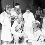 Private R.E. Pavely (lower right) of the 2nd Canadian Infantry Brigade talking with nurses and patients at a hospital in Avigliano, Italy, ca. 21-22 September 1943 [ca. September 21-22, 1943].