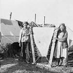 [Unidentified Cree or Inuuk standing next to sealskin being dried] Original title: Sealskin being dried by Indians at Fort George. Eskimos at Fort George are accepted into Indian camps as they are recognized as the best seal hunters 1949.