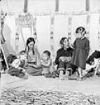 Two Tsuut'ina (Tsuu T'ina/Sarcee) First Nation women, from the One Spot family, with their grandchildren at Teepee Village, Victoria Park, during the Calgary Stampede July 1945.