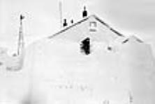 [Jerry Sperry outside the first church of Kuglutuk.] 1949-1950