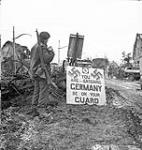 Corporal Urban Mayo, 13th Field Company, Royal Canadian Engineers (R.C.E.), with a sign that reads "You are entering Germany - be on your guard," Wyler, Germany, 9 February 1945 February 9, 1945.