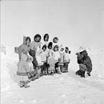 Inuit children line up to be filmed by Associated Screen News cinematographer Roy Tash, during Governor General Vincent Massey's northern tour Mar. 1956.