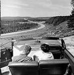 Young couple looking at travelling map in a convertible car n.d.