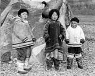 [Jayko Tunrak, Enoya Shooyook, and unknown chiild, outside a tent with a sealskin float].The younger generation n.d.