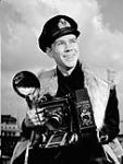 Lieutenant John D. Mahoney of the Royal Canadian Navy Volunteer Reserve, holding an Anniversary Speed Graphic camera 1944