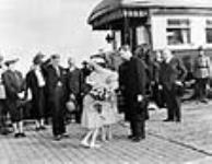 Joyce Evens, daughter of the City Clerk of Port Arthur, presents a bouquet to Queen Elizabeth, watched by Rt. Hon. W.L. Mackenzie King, Hon. C.D. Howe and Mayor C.W. Cox 23 May 1939