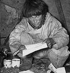 Inuit man reading a letter written in syllabics [John Pangniq, son of Hijerq] 1948.