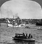 (Tricentenaire de Québec) Accompagné de canots amérindiens, le « Don-de-Dieu » arrive au port; il est en face de « La Place », maintenant appelée le quai du Roi, à Québec, au Québec 23 juillet 1908