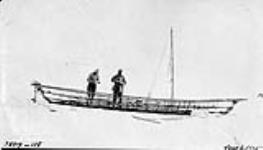 Umiak frame with mast set and Evinrude motor adjusted. J.R. Cox and J.R. Crawford, Bernard Harbour, N.W.T. [Nunavut], 6 June 1915 June 6, 1915.