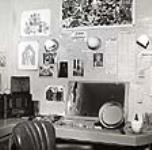 Gratien Gélinas étale des photographies sur la table, coupures de presse au mur - revue Fridolinons '45 [document iconographique] 1945