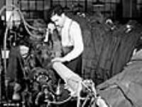Un homme repasse un uniforme de l'Armée canadienne dans une grande fabrique de vêtements canadienne déc. 1939