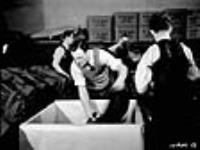 Workmen sort and pack finished Canadian Army uniforms in preparation for shipping them to Army headquarters déc. 1939
