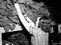Une femme trie des uniformes militaires destinés aux entrepôts de l'armée déc. 1939