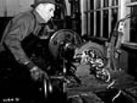 Douille de fusil-mitrailleur Bren. Dans une usine de munitions du Canada, un machiniste fait fonctionner un tour qui rase la douille moulée aux dimensions requises, laissant une bourrelet à l'extrémité qui tient la douille dans le fusil Dec. 1939