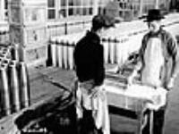 Douilles de fusil-mitrailleur Bren. Des ouvriers appliquent une couche depeinture sur des douilles pour les protéger de la corrosion à l'usine de munitions de la National Steel Car Corporation Ltd Dec. 1939
